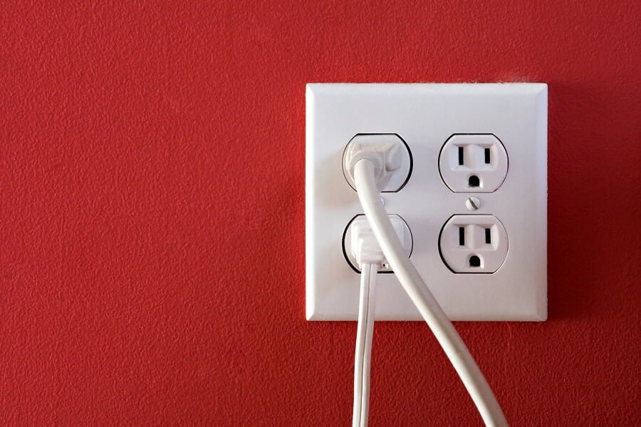 Electrical outlets with four spaces and two of them have chords plugged in.